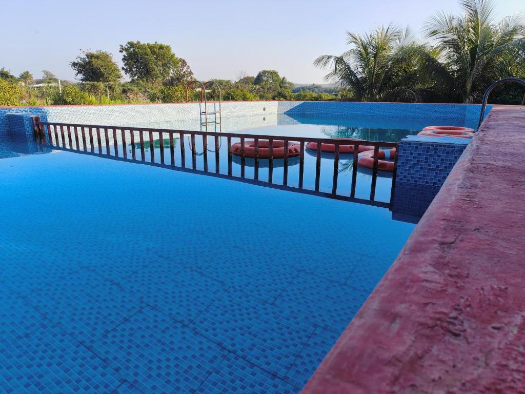 萨三吉尔Gokul farm house的蓝色海水游泳池和围栏