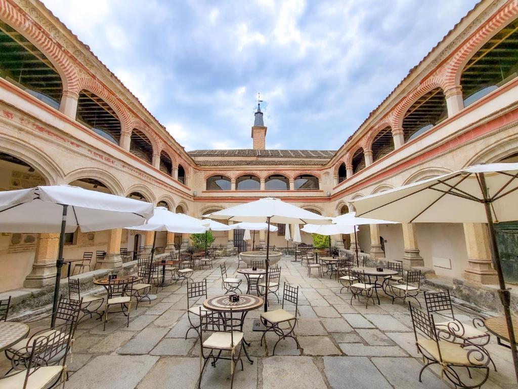 塞哥维亚圣安托尼奥皇家酒店的一座带桌椅和遮阳伞的空庭院