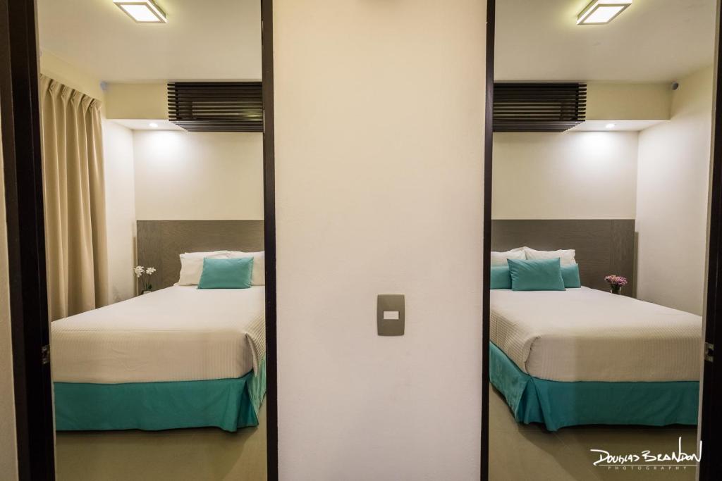瓦哈卡市Marialicia Suites, Hotel Boutique的配有2张床的客房内的镜子