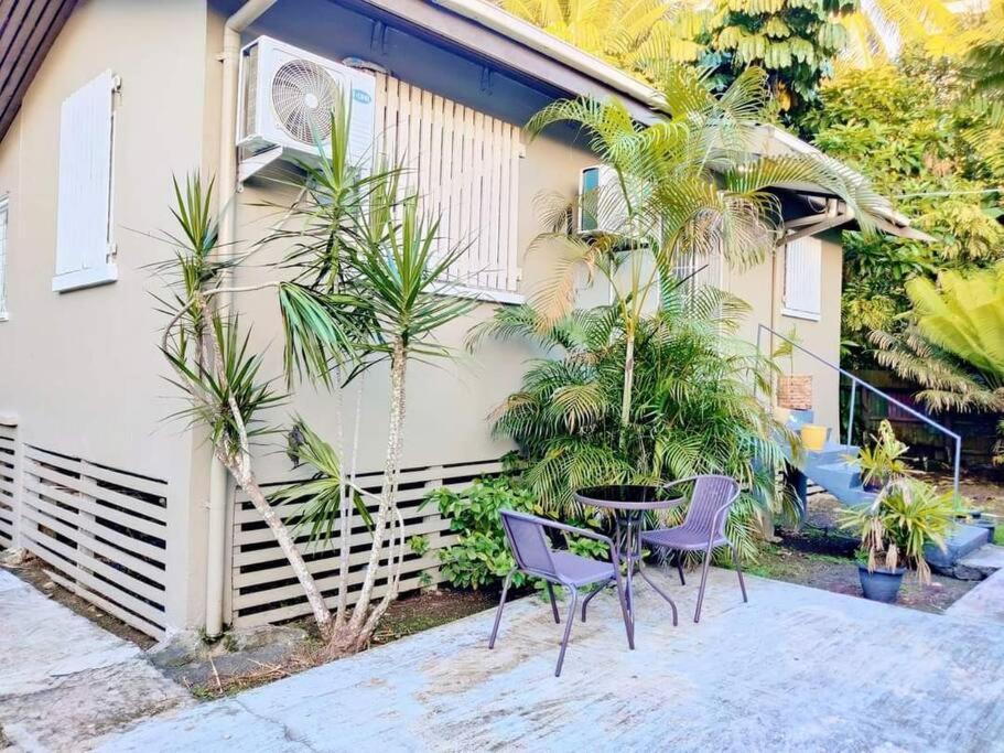 苏瓦Guesthouse in Suva的房屋前设有带2把椅子和1张桌子的庭院。
