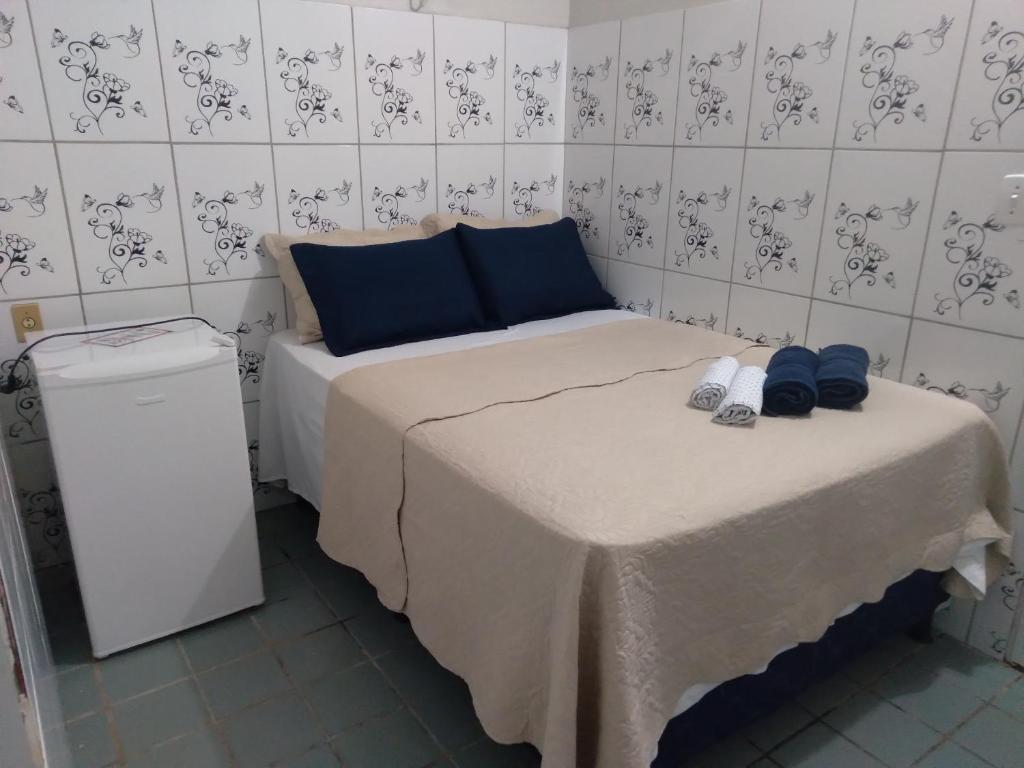 加利纽斯Pousada Pôr do Sol - Galinhos的小房间,配有带蓝色枕头和鞋子的床