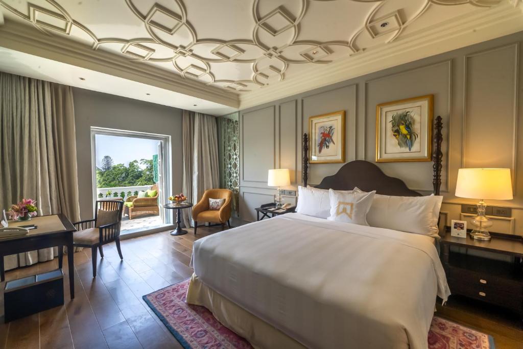班加罗尔ITC Windsor, a Luxury Collection Hotel, Bengaluru的一间带一张大床和一张书桌的卧室和一间房间
