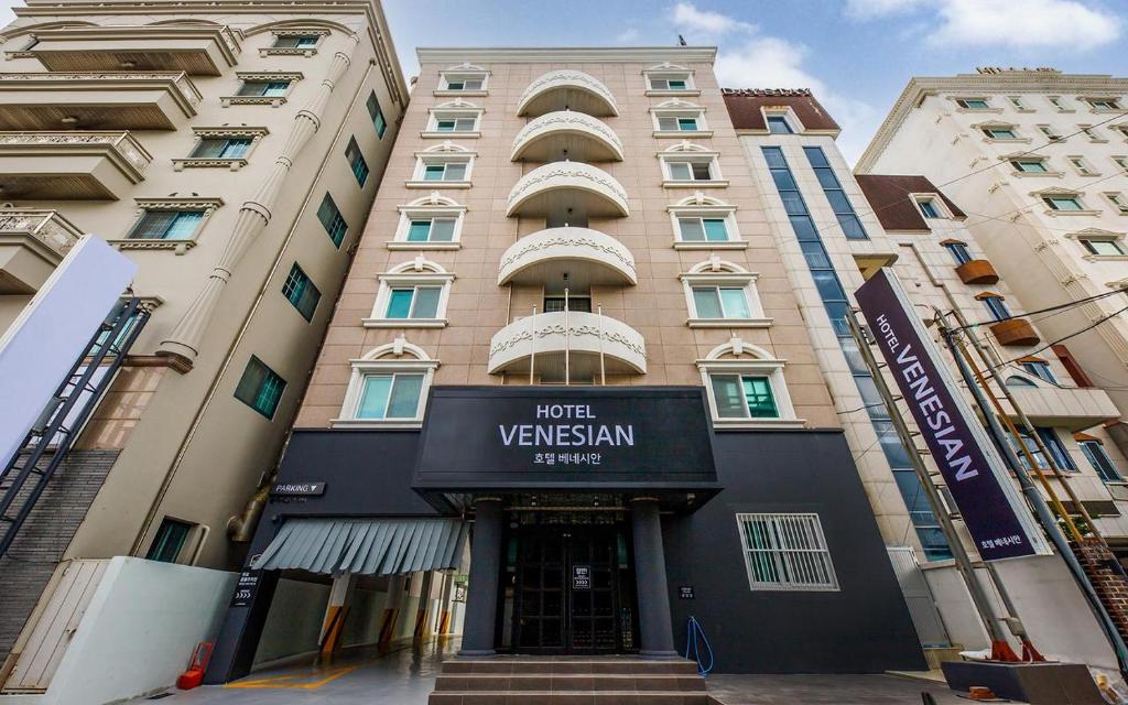 浦项Hotel Venesian的一座高大的公寓楼,上面有酒店维斯的标志