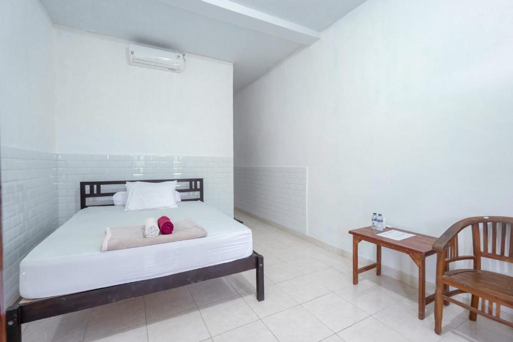 乌鲁瓦图SDK Homestay Uluwatu的卧室配有1张床、1张桌子和1把椅子
