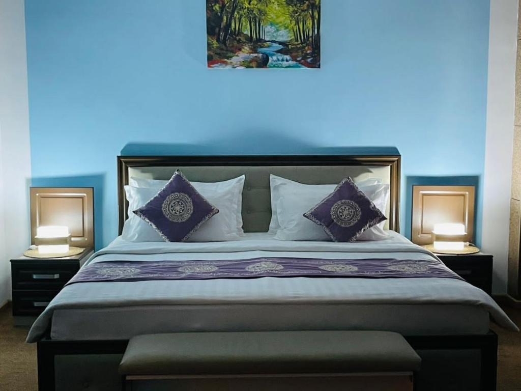 杜尚别Hotel Shumon的一间卧室配有一张带紫色枕头的大床