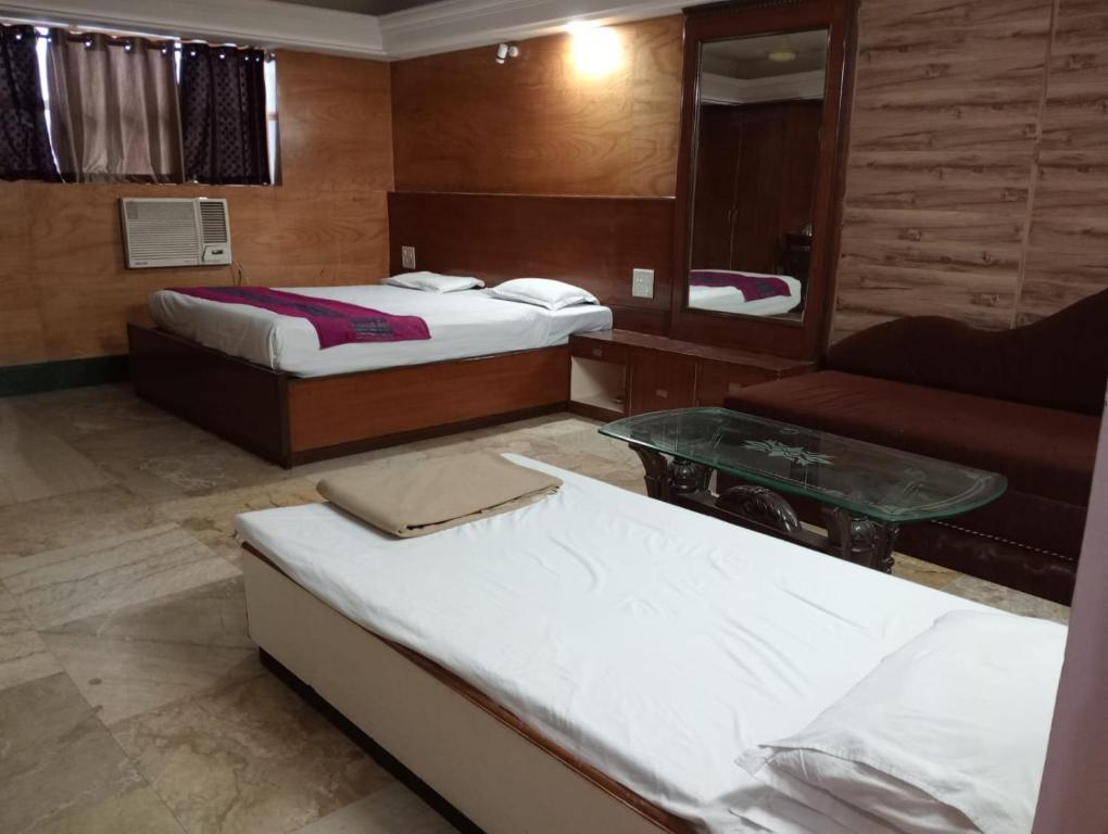 瓜廖尔Hotel Sun Beam Near Gwalior Railway Station的酒店客房,设有两张床和一张沙发