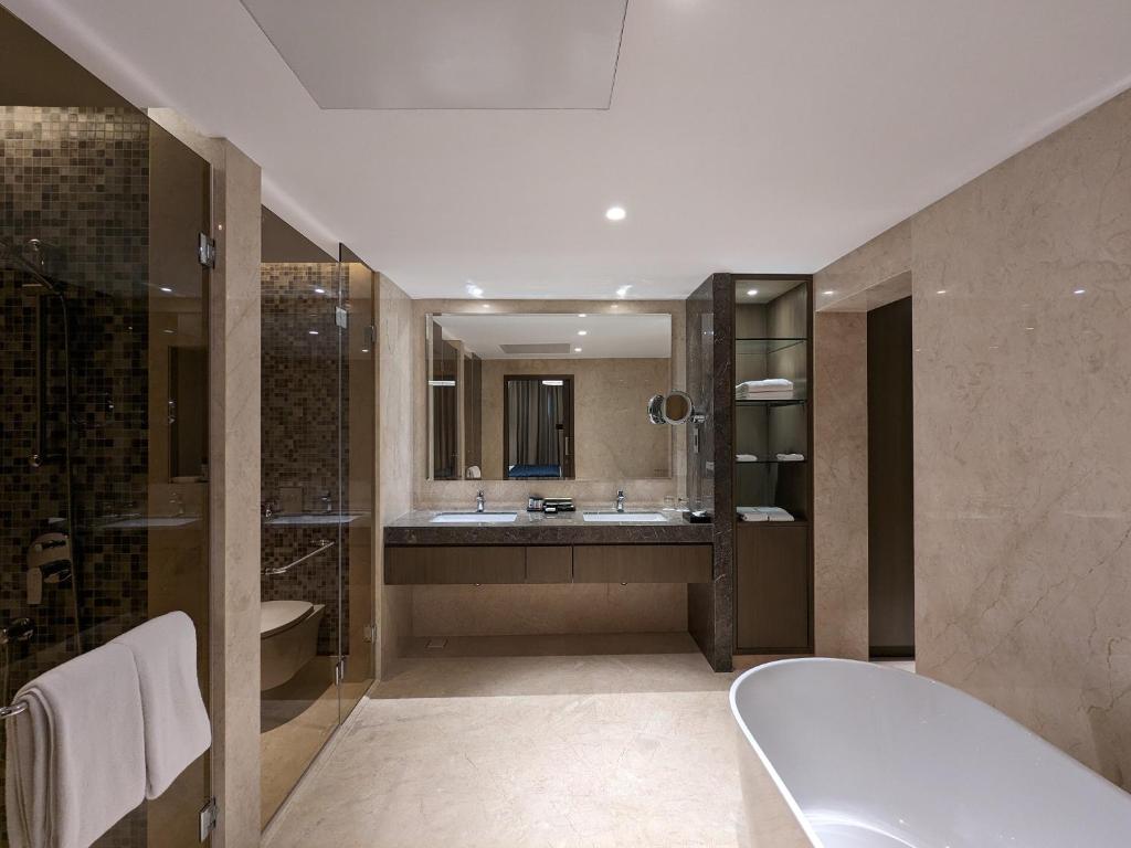 班加罗尔Palm Meadows Resort的带浴缸、水槽和淋浴的浴室