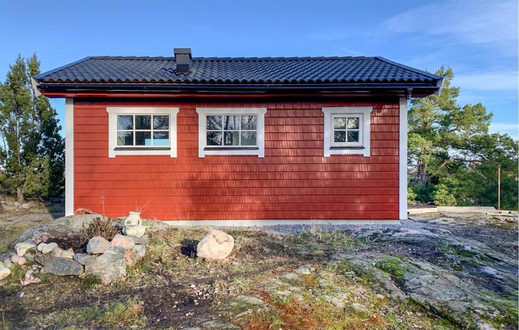 玛丽费莱德Amazing Home In Mariefred With Kitchen的一座红色的小房子,在田野上有两个窗户