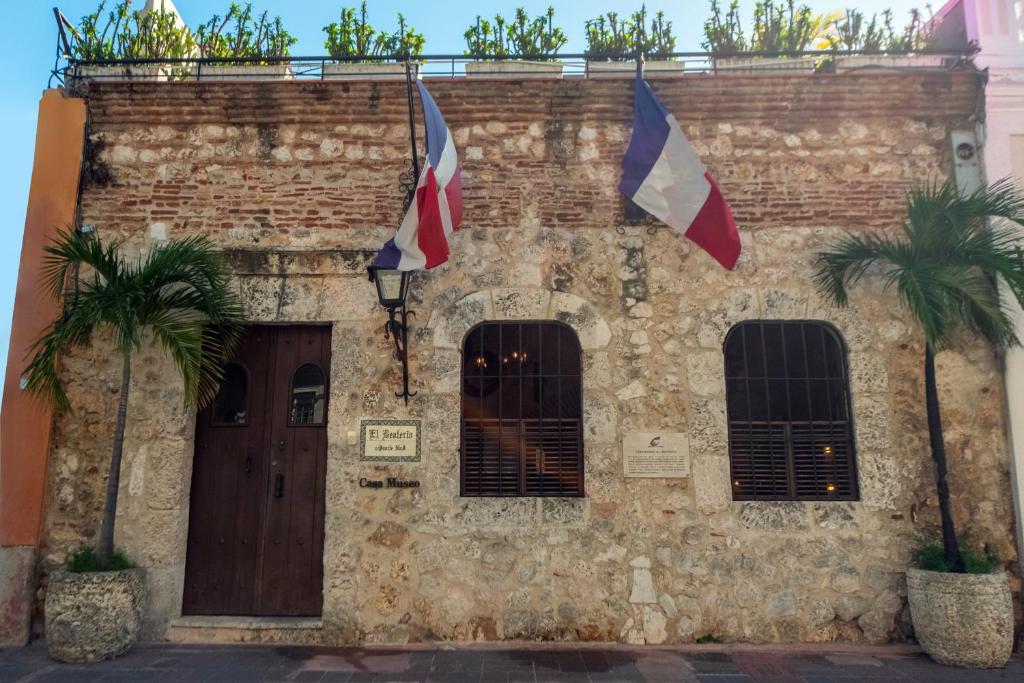 圣多明各埃尔比特里欧卡萨博物馆酒店的一座砖砌建筑,上面有旗帜,两棵棕榈树