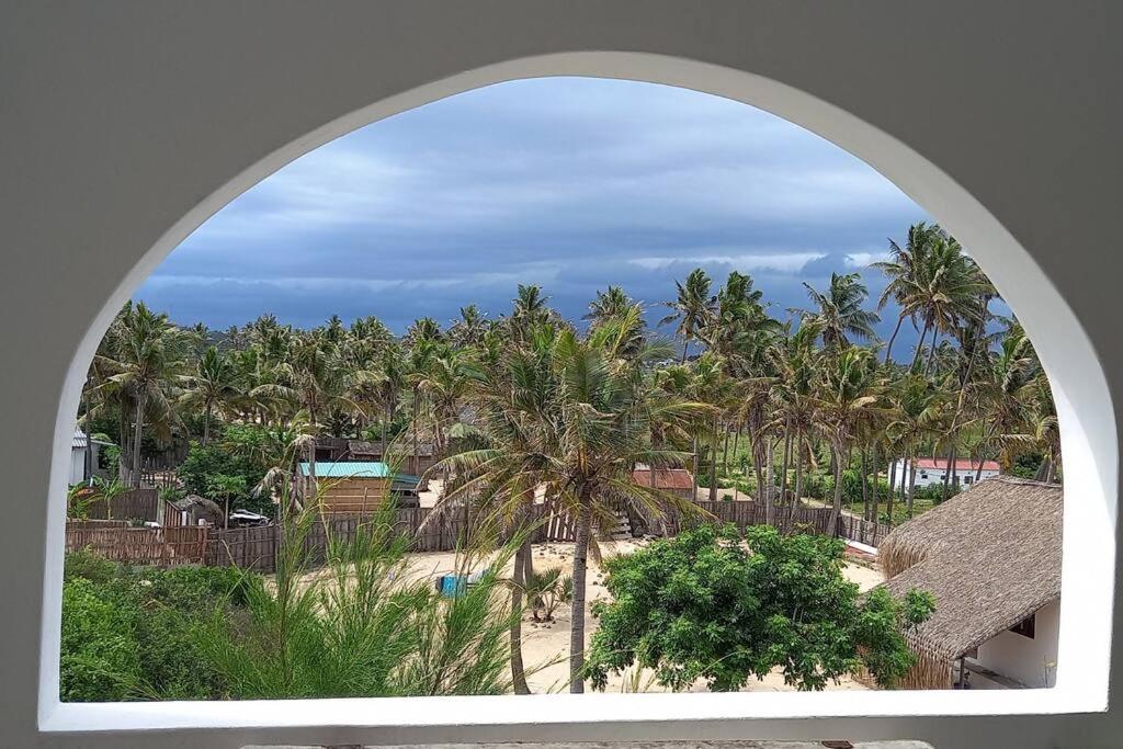 托弗海滩Beachfront Villa in Tofo Beach, Mozambique的拱形窗户享有棕榈树海滩的景致