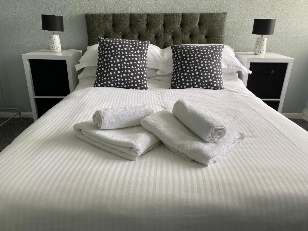 莫克姆Quiet Ground Floor apartment with parking的一张带毛巾和枕头的白色床