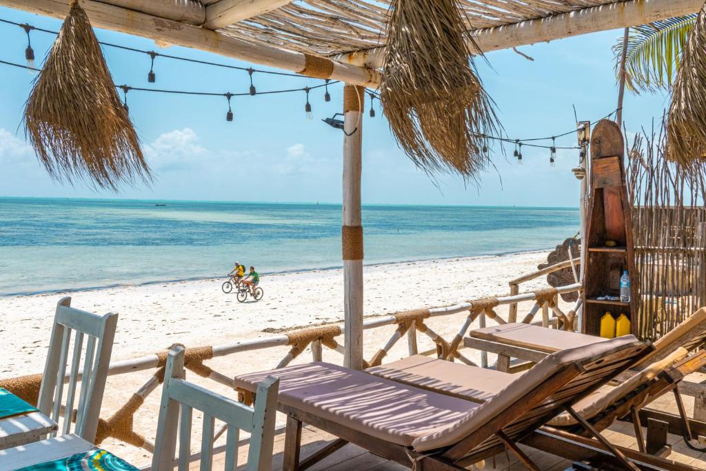 江比阿Pili Pili Sunrise的海滩上设有两把椅子和一把遮阳伞,大海上设有