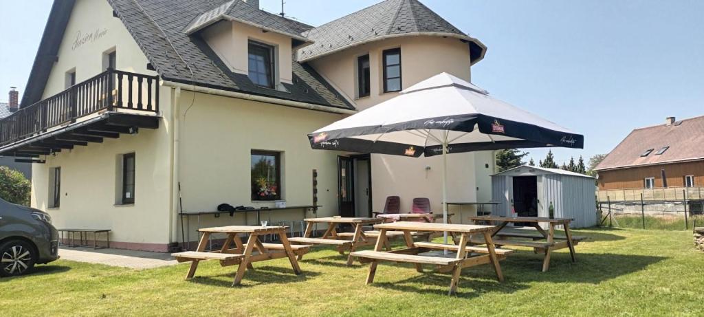 Město Albrechtice玛丽旅馆的一组野餐桌和一把伞,位于房子前面