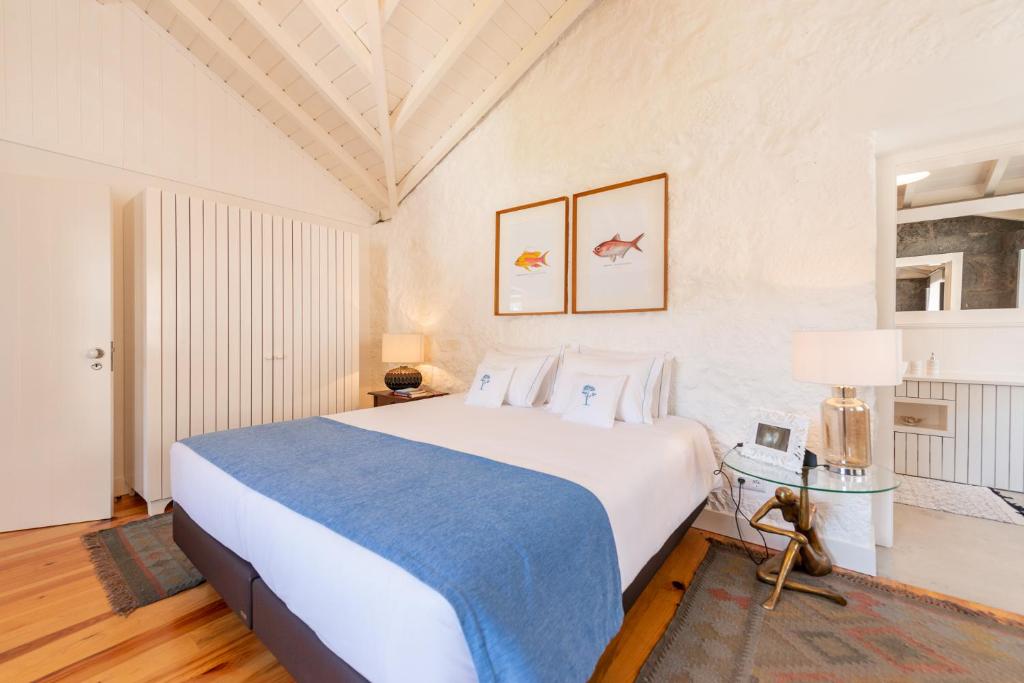 Calheta de NesquimT1 Casa das Pereiras的一间卧室配有一张大白色床和蓝色毯子