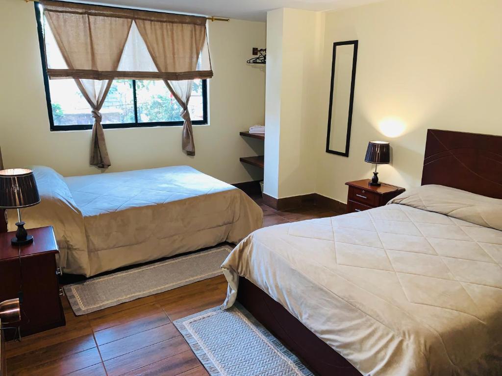 基多Hostal Casa San Fernando Tumbaco的一间卧室设有两张床和窗户。