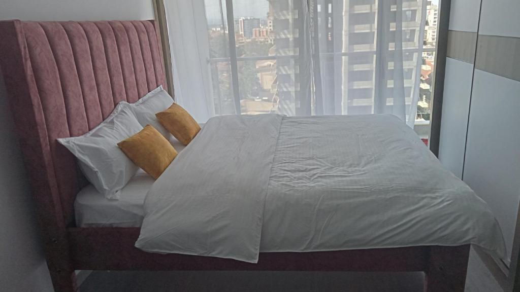 内罗毕Lovella Suites Gold Park的一张位于带大窗户的房间内的床铺