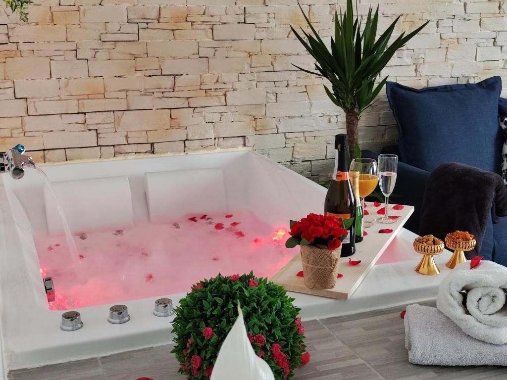 米卢斯Romantic Cocon Home in Mulhouse的浴缸配有粉红色水和酒杯