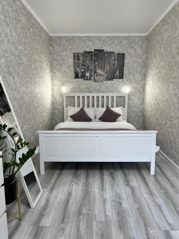 阿斯塔纳Уютная квартира ЖК Сказочный мир город Астана的卧室配有白色的床和木地板