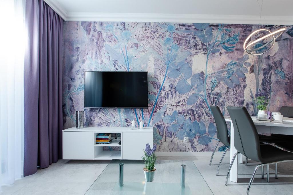 济夫努夫Apartament LAWENDOWY Gardenia Dziwnów z widokiem na morze EPapartamenty的一间客厅,在紫色的墙上配有电视