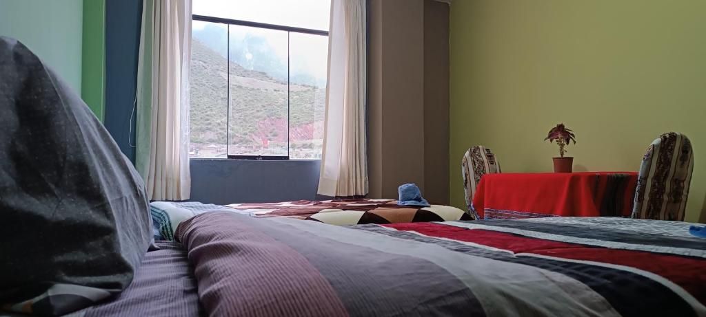 奇瓦伊Hospedaje Vacacional - Colca的客房设有两张床、一张桌子和一扇窗户。