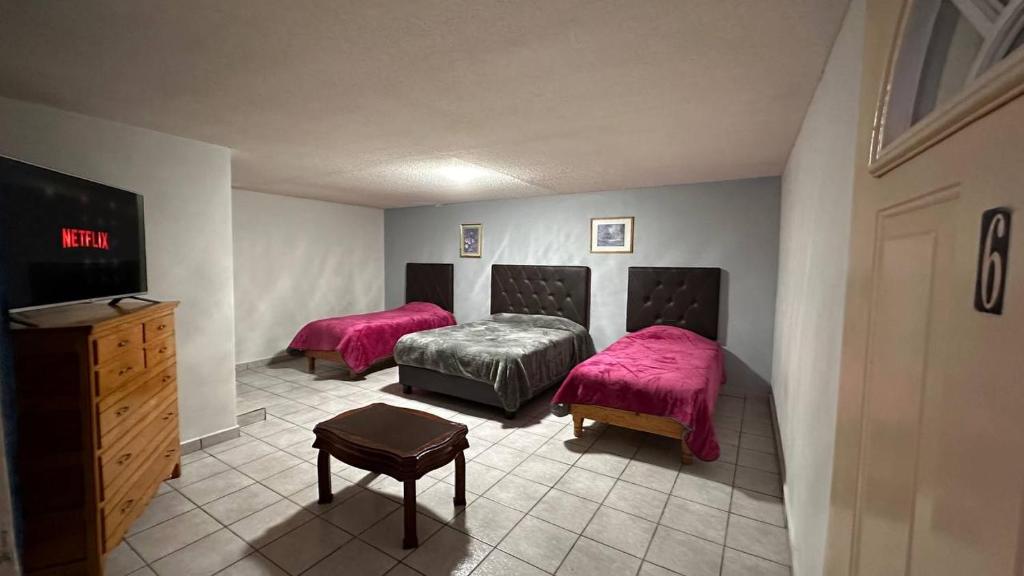 Hotel y Cabañas Cascada de Basaseachi的客房设有两张床和一张带粉红色床单的梳妆台。