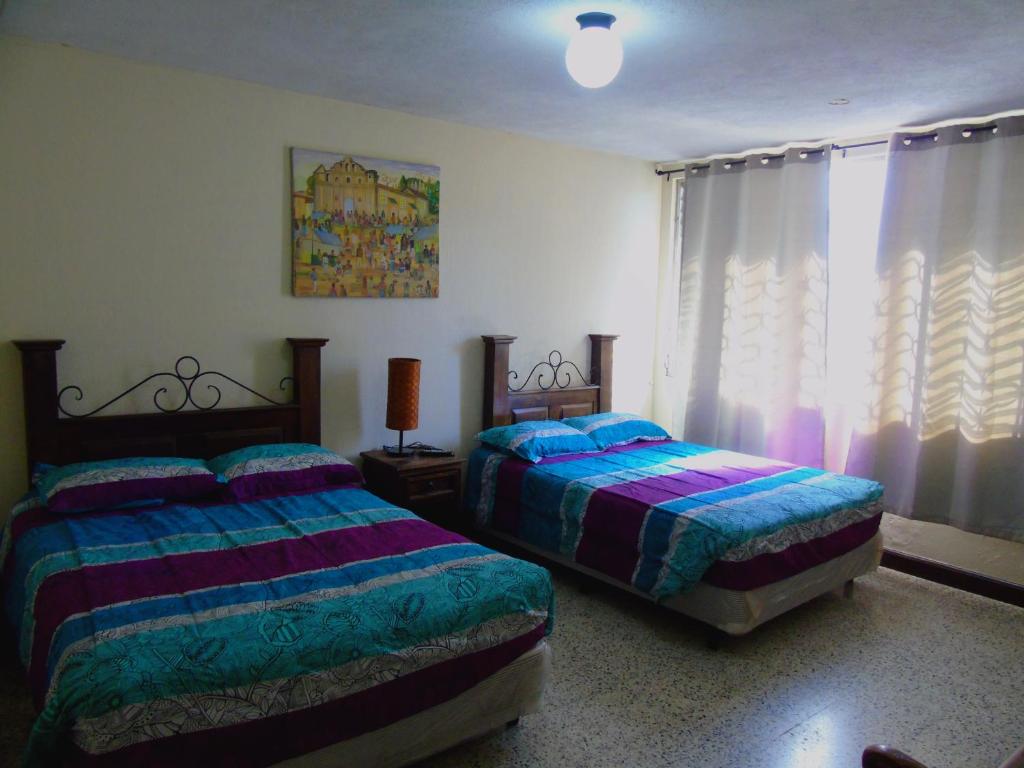 危地马拉Hostal Los Volcanes的一间卧室设有两张床,窗户配有窗帘