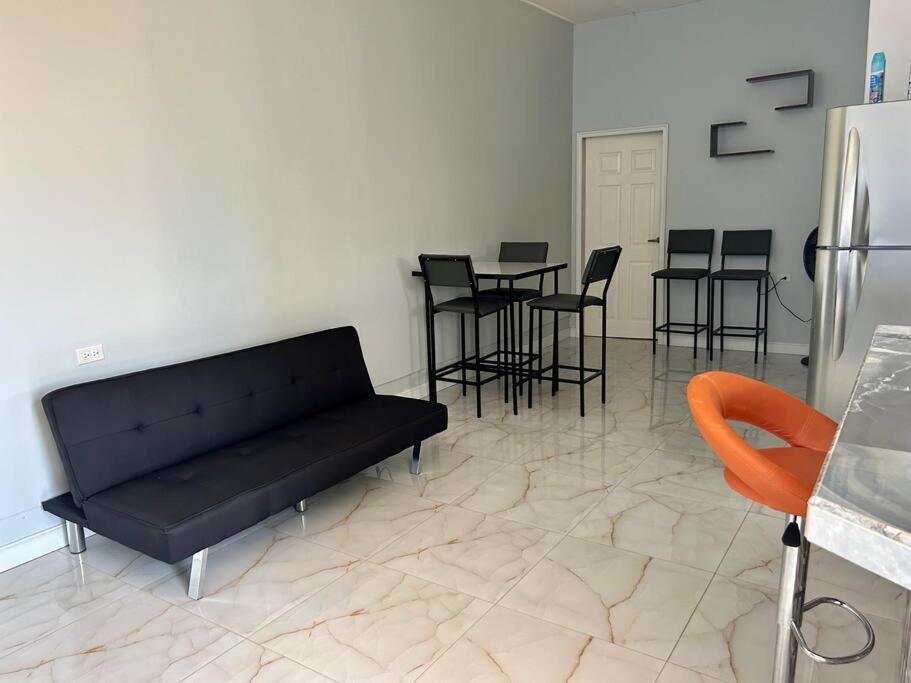 PiarcoPiarco Airport Guest House的一张黑色沙发,位于带桌椅的房间里
