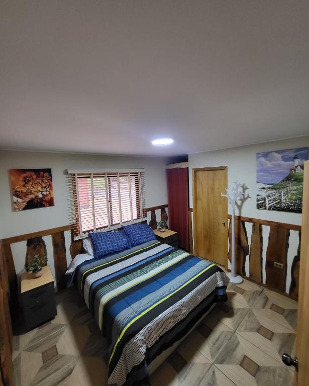 普孔Cabañas Condominio El Bosque的一间卧室配有一张带蓝色枕头的床和一扇窗户。