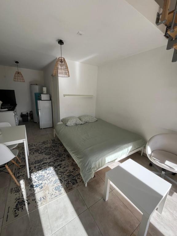 RoaixGuest house en Provence的一间卧室配有一张床铺、一张桌子和一台冰箱