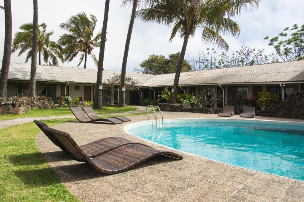 安加罗阿Hotel Hotu Matua的一座房子旁的游泳池,配有两把躺椅