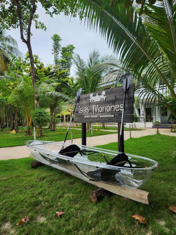 ManiwayaIslas Moriones Beach Resort的坐在草上标志旁的船