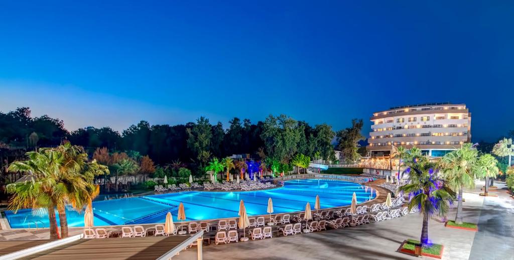 科纳克勒Bera Alanya Hotel - Halal All Inclusive的享有带椅子和棕榈树的度假村游泳池的顶部景致