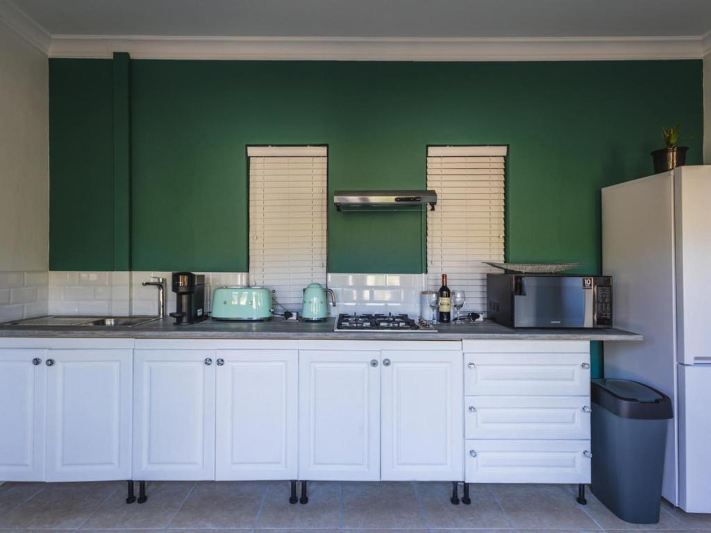 普利登堡湾Cliffside Suites的厨房配有白色橱柜和绿色墙壁