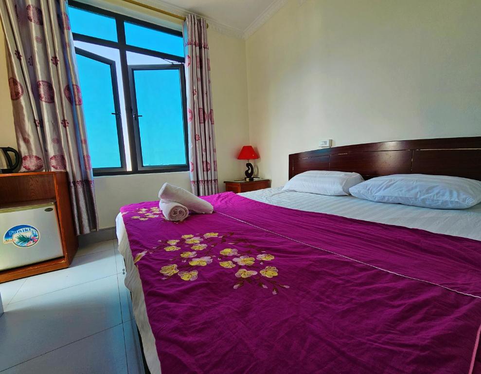 Dien Bien PhuFrontier Hostel & Tours的一张床上,上面有鲜花,上面有紫色毯子