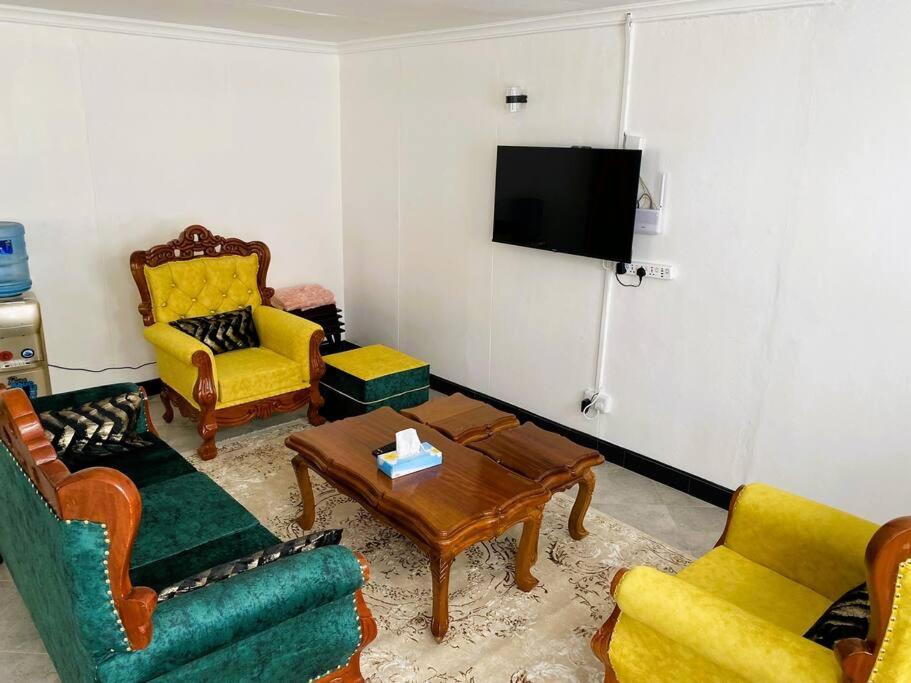 纳库鲁3 Bedroom Laneens Nest的客厅设有黄色和绿色椅子和电视