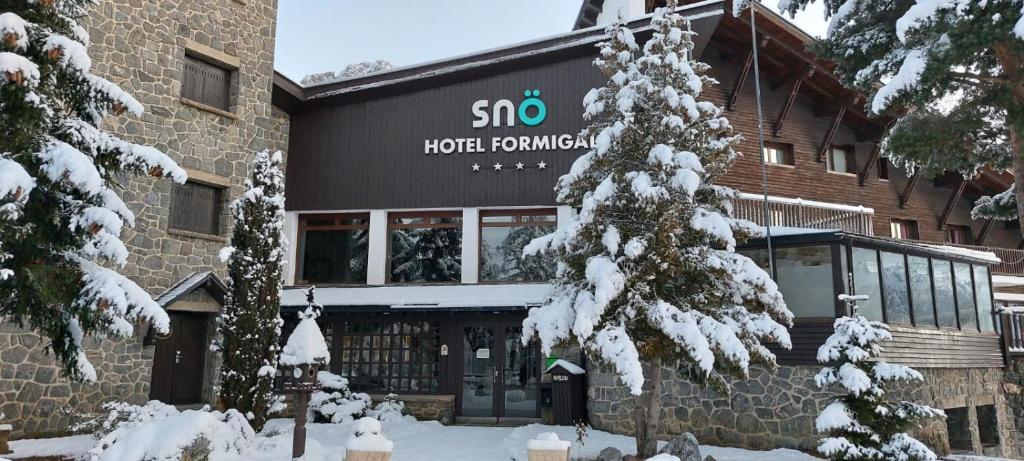 福米加尔Snö Hotel Formigal的酒店大楼前面有雪覆盖的树木