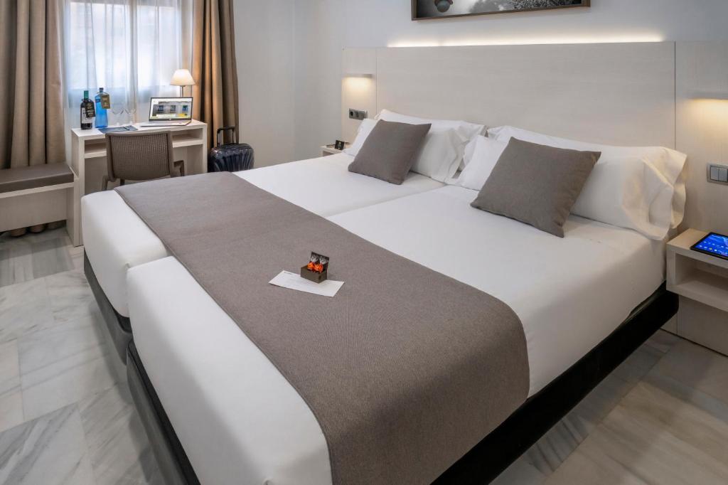 巴塞罗那SERHS Carlit Boutique Hotel的一张大白色的床,位于带书桌的房间里