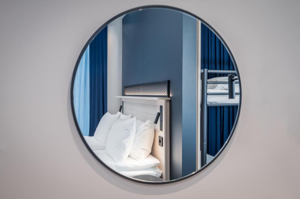 赫尔辛基Citybox Helsinki的墙上的圆镜子,房间里的床