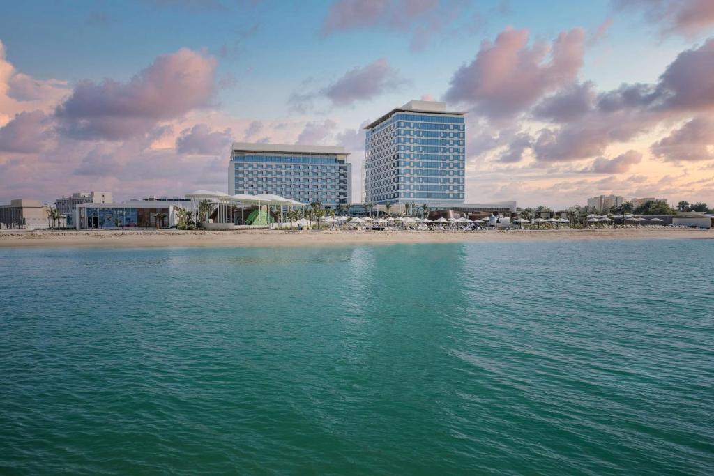 多哈Rixos Gulf Hotel Doha的享有海滩、建筑和大海的景色