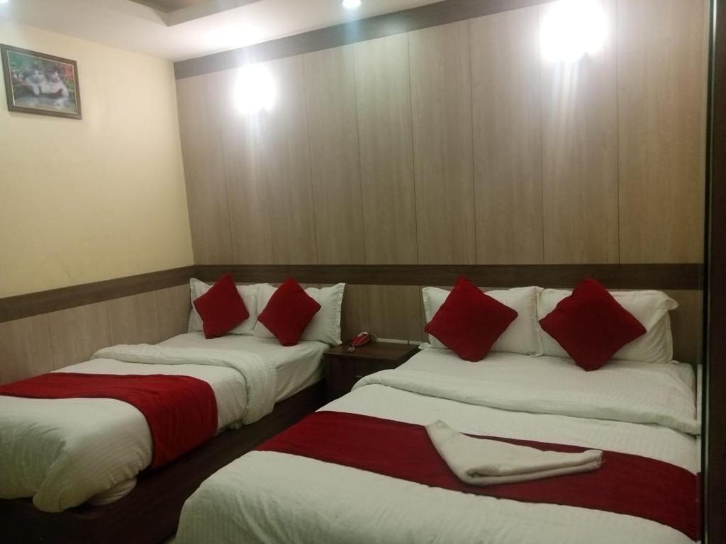 加德满都Hotel C O International的两张位于酒店客房的床,配有红色和白色枕头