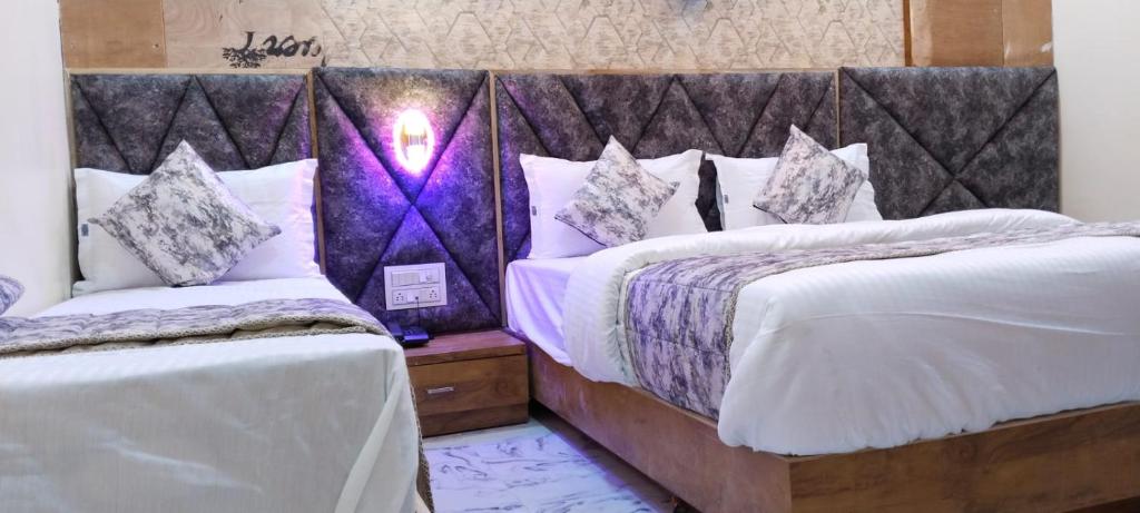 艾哈迈达巴德Hotel Primeland villa Gota的一间卧室配有两张带白色和紫色枕头的床