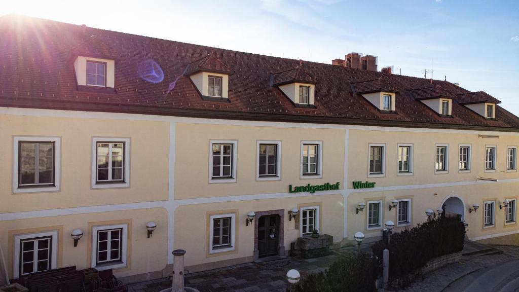 Ardagger StiftLandgasthof Winter的白色的大建筑,带有棕色的屋顶
