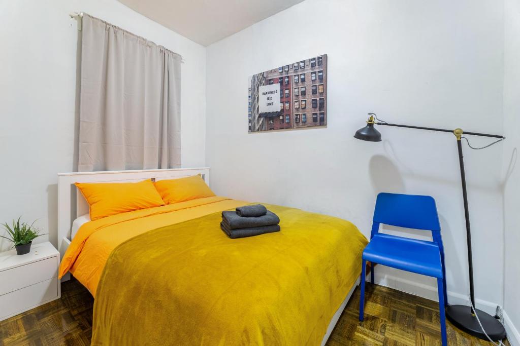 纽约Modern NY Style 2BD Apartment in Upper East Side Manhattan的一间卧室配有黄色的床和蓝色椅子