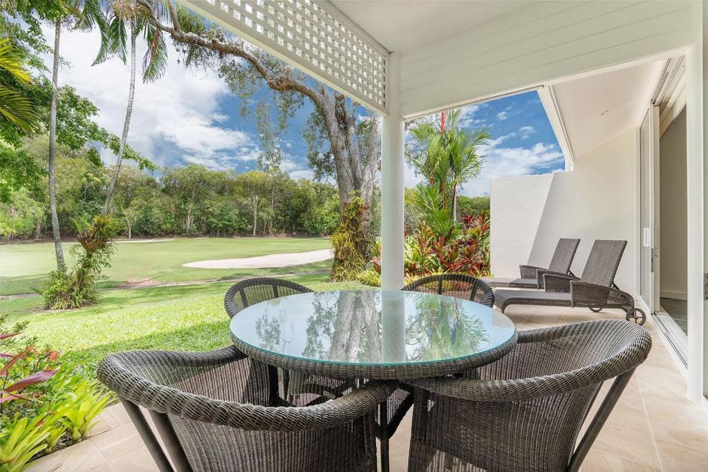道格拉斯港Tropical Resort-style Living on Mirage Golf Course的一个带玻璃桌和椅子的庭院
