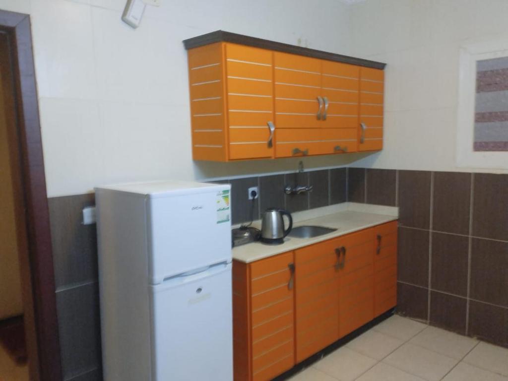 吉赞نون للشقق المفروشة的厨房配有白色冰箱和木制橱柜。