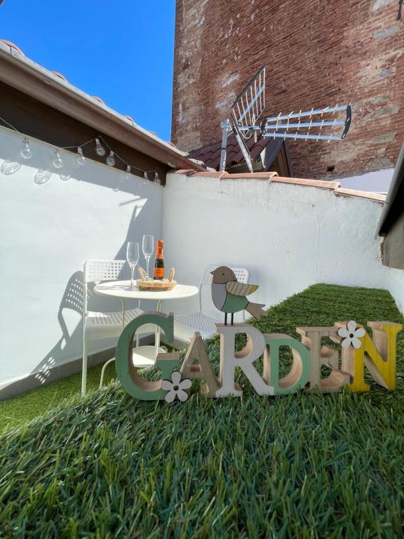 都灵Garden House Cit Turin的草上的一个标志,上面有桌子和鸟
