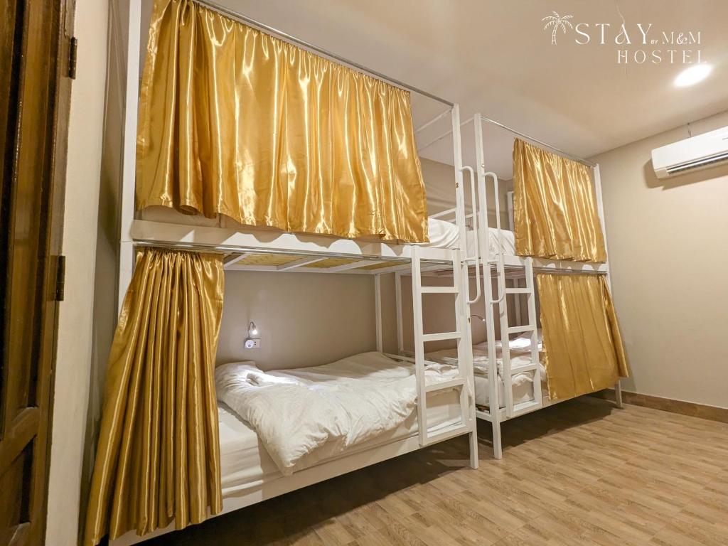 他曲STAY Hostel & Motorbike Rental - Thakhek的一间卧室设有两张双层床,配有黄色窗帘