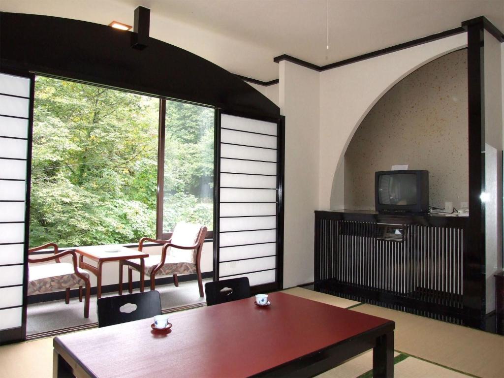 雫石町Oshuku Onsen Hotel Uguisu - Vacation STAY 27299v的配有桌椅和电视的客房