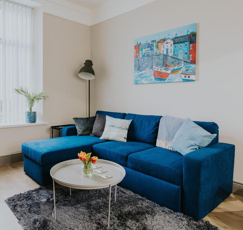 纽卡斯尔BlueSeaView Apartment with fabulous sea views的客厅配有一张蓝色的沙发,配有一张桌子