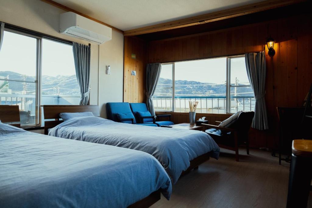 热海Atami-Ajironokaze - Vacation STAY 87959v的酒店客房带两张床、一张桌子和椅子。